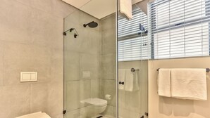 Une salle de bain moderne avec une douche à parois de verre, des toilettes et un porte-serviettes.