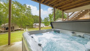 A hot tub under a wooden pergola with a view of a lake and houses in the background. - New! Family time. Hot Tub, Pool Table, Firepit, Dock, Kayaks. Screened Porch (Bracey)
