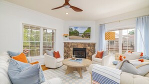 A living room with white furniture, a stone fireplace, and large windows. - New! Family time. Hot Tub, Pool Table, Firepit, Dock, Kayaks. Screened Porch (Bracey)