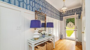 A hallway with a white console table, two lamps, a mirror, and wicker baskets. - New! Family time. Hot Tub, Pool Table, Firepit, Dock, Kayaks. Screened Porch (Bracey)