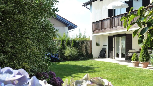 A well-maintained garden with a lawn, potted plants, and a variety of shrubs. - Ferienwohnung Lehmann 58 qm, Erdgeschoss, mit Terrasse und Separatem Schlafzimmer (Bad Endorf)