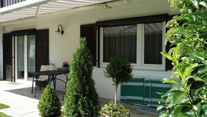 A patio with a table and chairs, potted plants, and a sliding glass door. - Ferienwohnung Lehmann 58 qm, Erdgeschoss, mit Terrasse und Separatem Schlafzimmer (Bad Endorf)