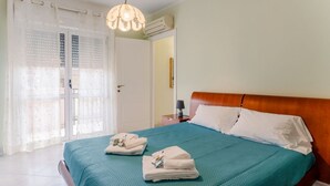 Et hotelværelse med seng, et natbord, en lampe og et vindue med gardiner.