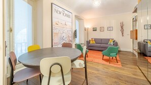 A dining area with a round table and chairs, a sofa, and a framed map on the wall. - GuestHost - Corso Vittorio Central & Roomy Flat x4 (Torino)