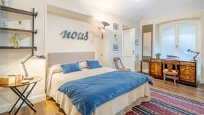 A bedroom with a bed, bedside table, lamp, dresser, and a wall with the word 'nous' on it. - GuestHost - Corso Vittorio Central & Roomy Flat x4 (Torino)