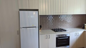 A modern kitchen with a stainless steel refrigerator, a gas stove, and a built-in oven. - 1 bedroom guesthouse near airport with private access and parking (Arncliffe)