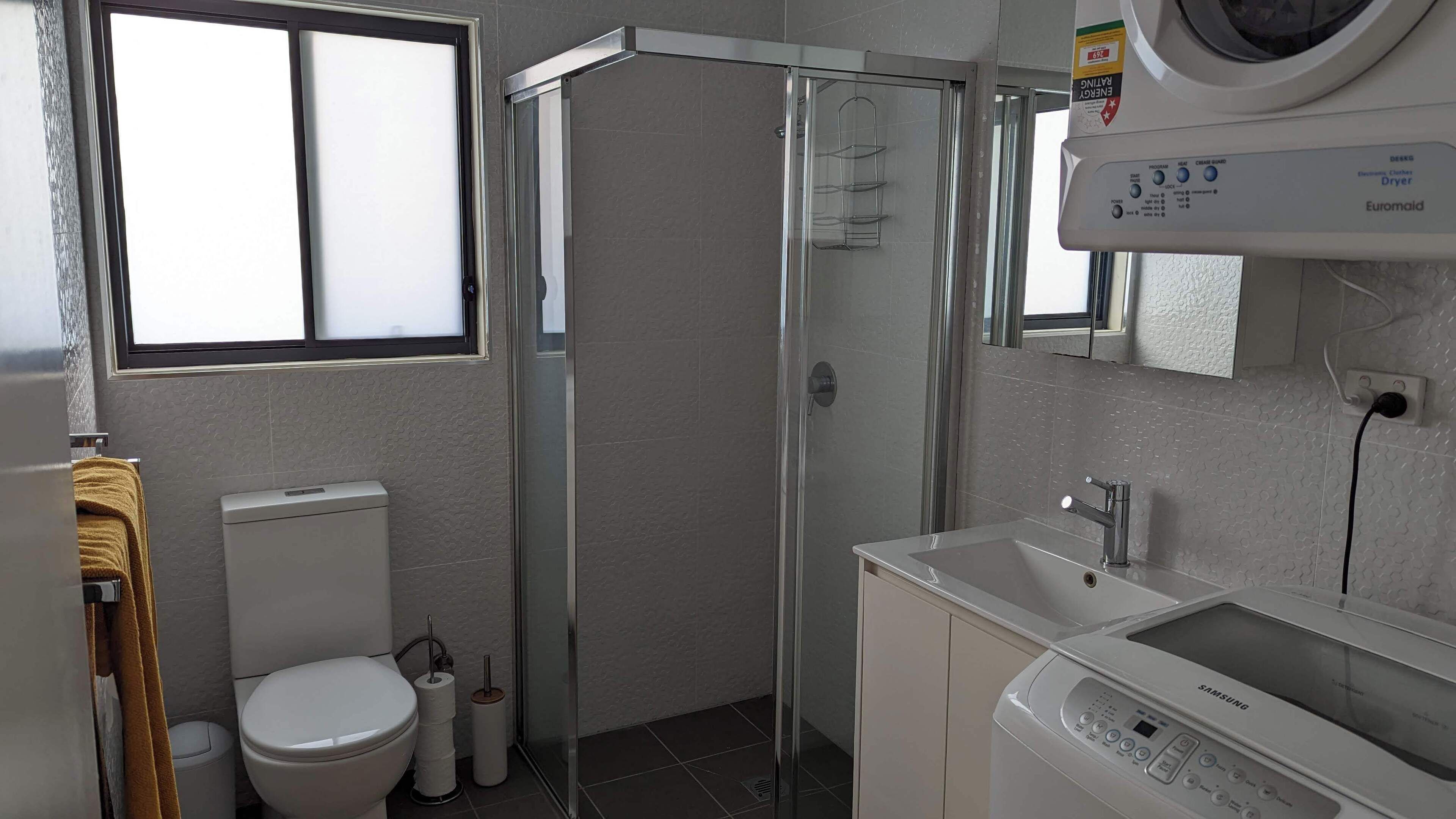 Un baño moderno con inodoro, lavabo y cabina de ducha con mampara de vidrio.