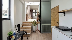 A modern kitchen with a refrigerator, a dining table with chairs, and a potted plant. - HoLo Ben Thanh Saigon - Serviced HomeStay (Ho Chi Minh City)