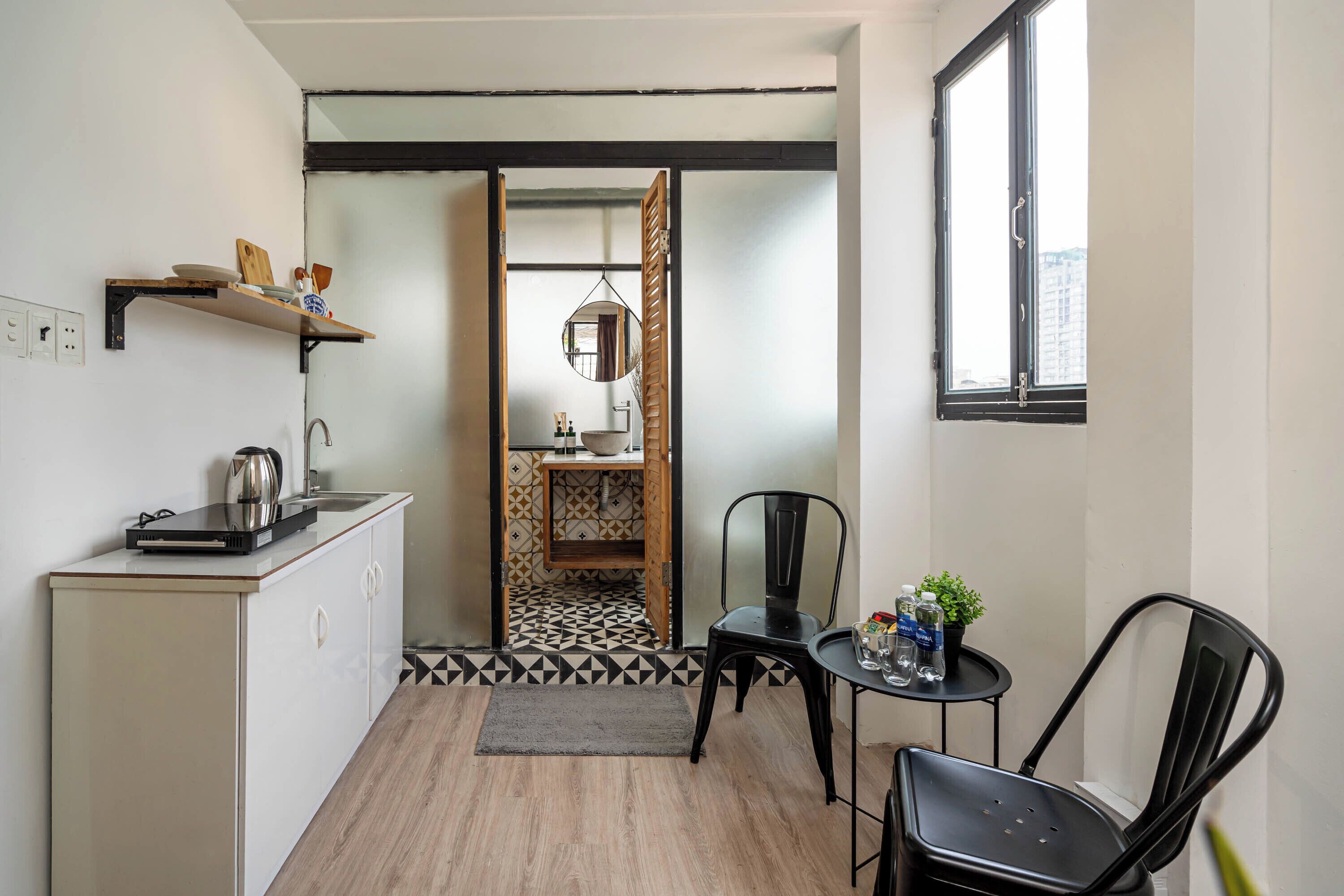 A compact kitchen with a countertop, a sink, and a small cabinet. There is a window with a view of buildings outside.