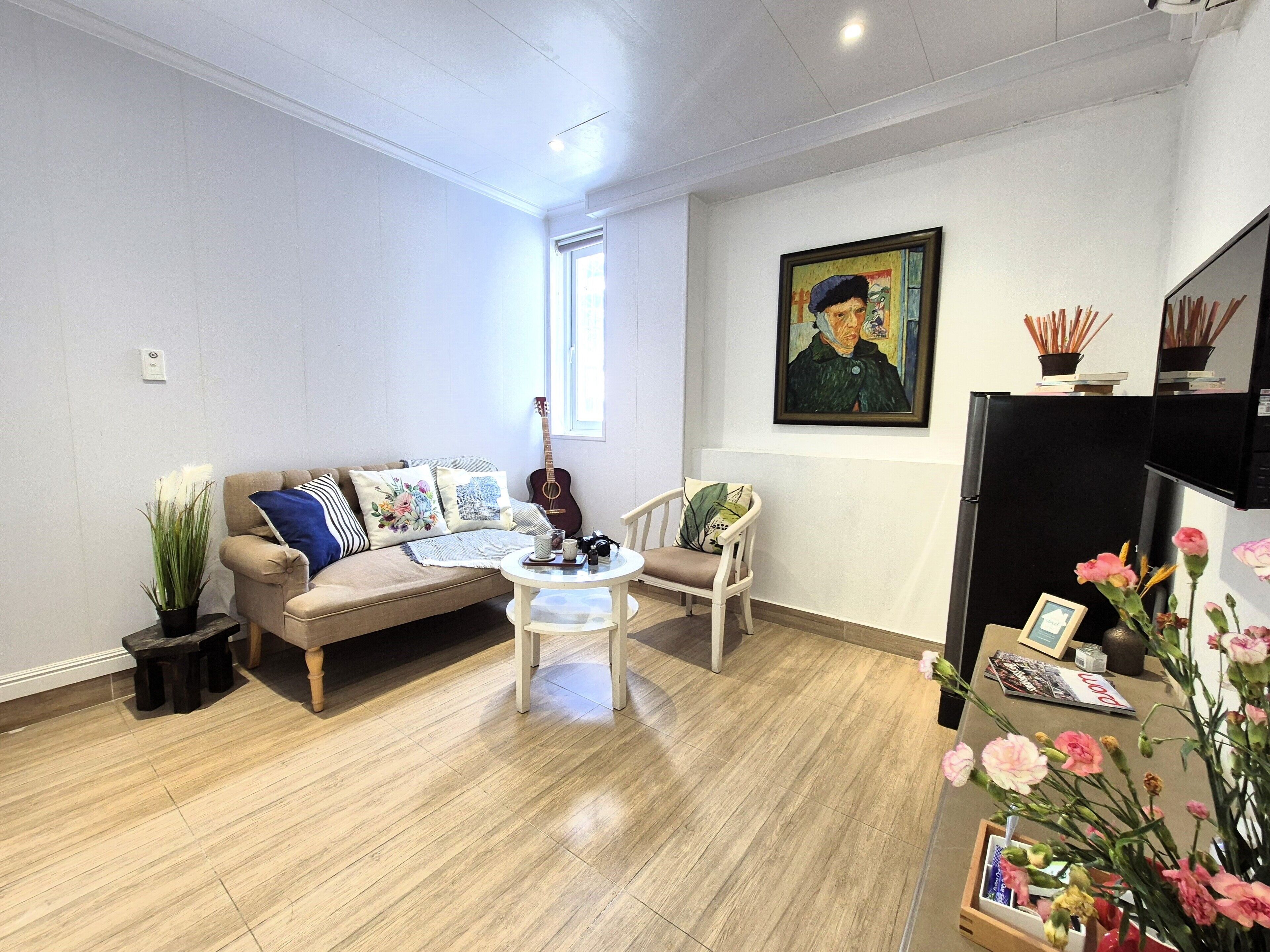 Un salon avec un canapé, des fauteuils, une table basse, une guitare et un tableau accroché au mur.