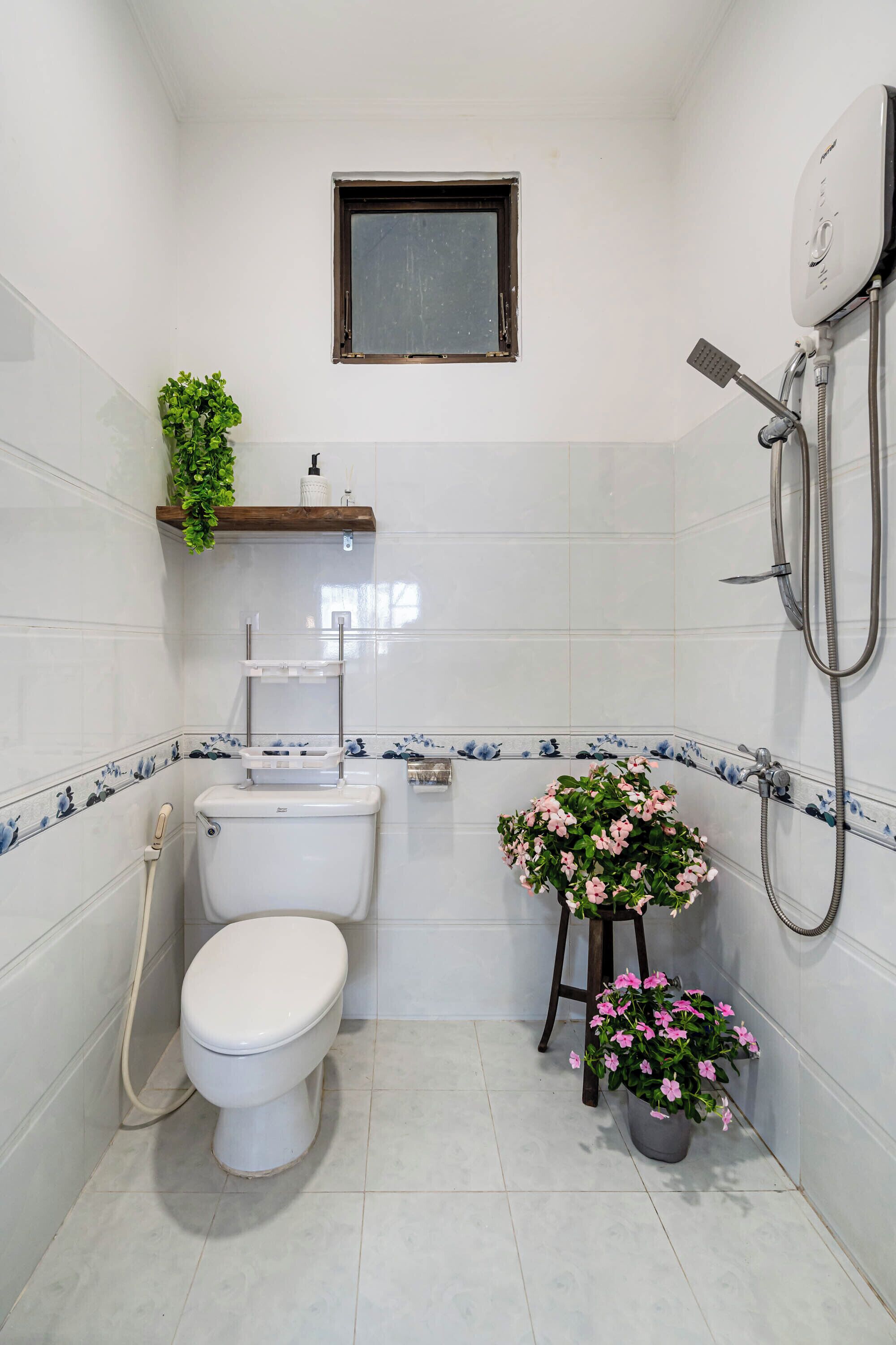 A small bathroom with a toilet, a shower, and a window.