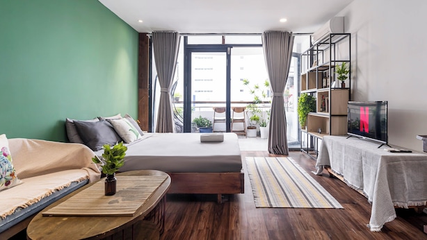 A modern bedroom with a bed, sofa, and a TV. - HoLo Ben Thanh Saigon - Serviced HomeStay (Ho Chi Minh City)