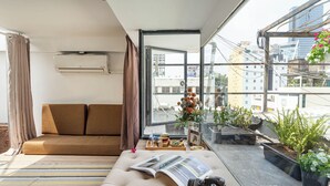 A modern living room with a sofa, a coffee table with decorative items, and a view of the city through large windows. - HoLo Ben Thanh Saigon - Serviced HomeStay (Ho Chi Minh City)