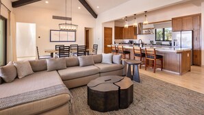 A spacious living area with a large sofa, a dining table, and a kitchen with wooden cabinets and modern appliances. - Luxurious 4BR Casita – Your Perfect Getaway! (Cabo San Lucas)