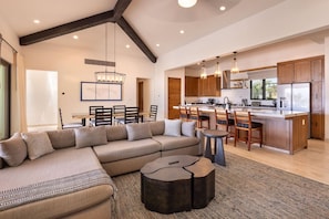 A spacious living area with a large sofa, a dining table, and a kitchen with wooden cabinets and modern appliances.