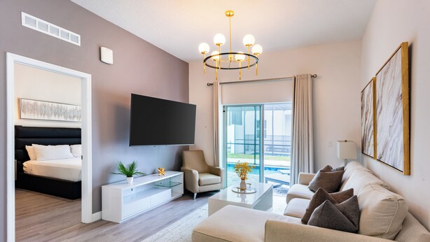 Une chambre d’hôtel moderne équipée d’un téléviseur à écran plat, d’un canapé, d’une table basse et d’un lit avec une tête de lit.