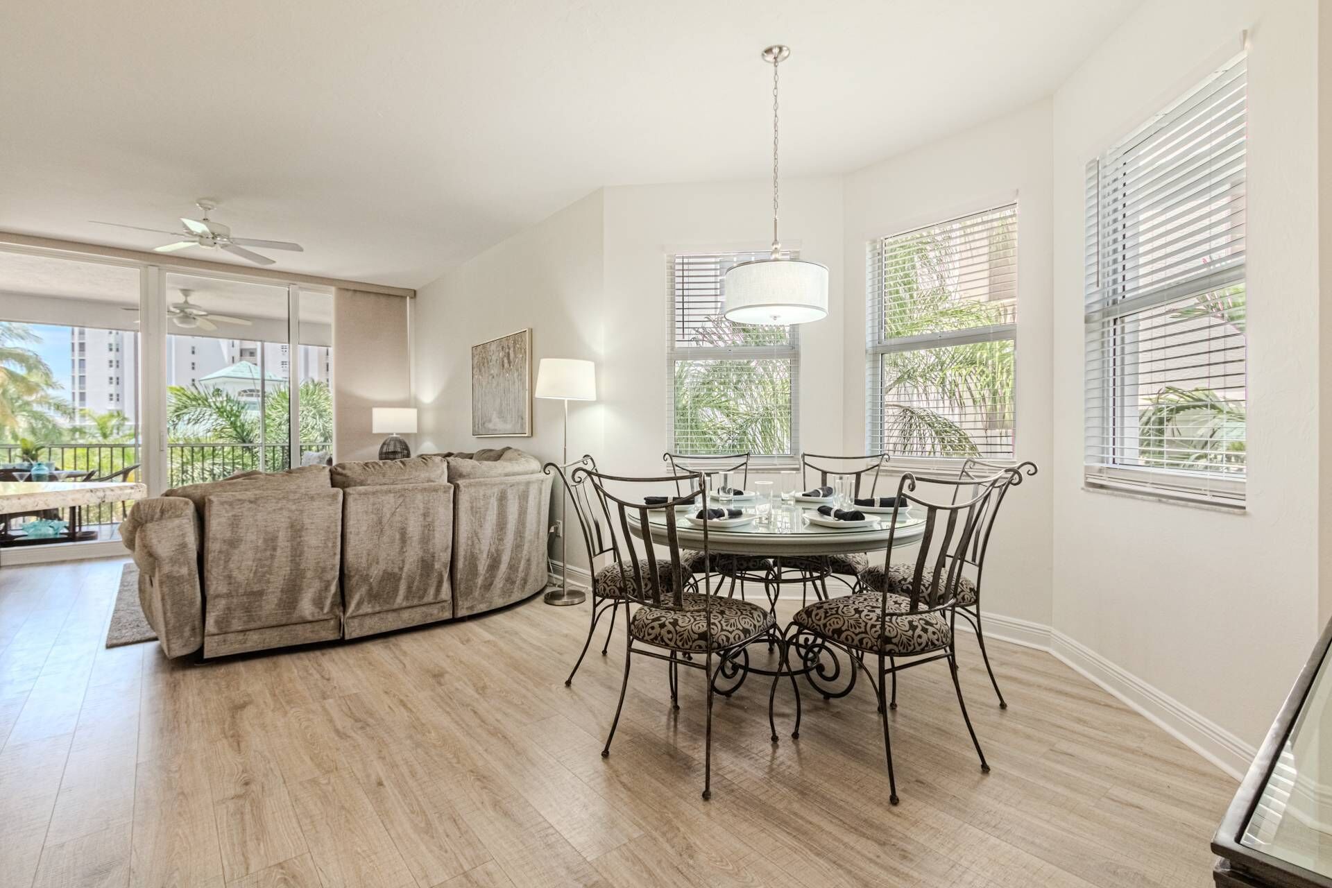 A spacious living area with a round dining table, cushioned seating, and a ceiling fan.