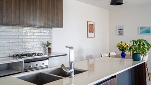 Et moderne køkken med en central ø, rustfrie hårde hvide fliser.