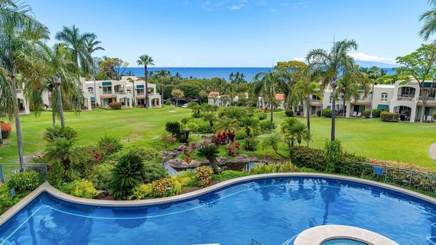 A resort with a swimming pool, lush greenery, and a view of the ocean. - New! Palms 702 - Romantic Retreat - Split AC in Bedroom - Open-Air Living Area (Kihei)
