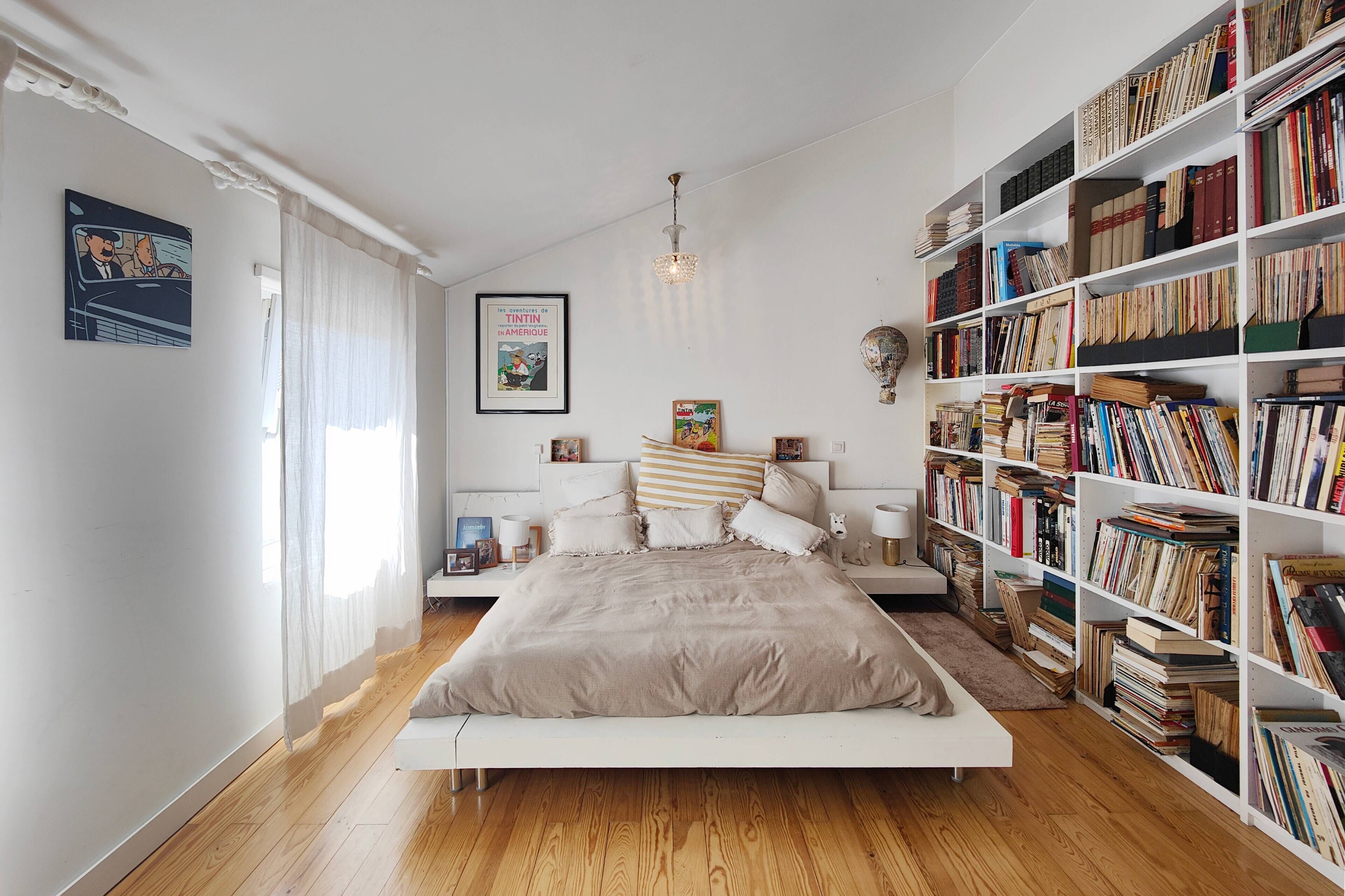 Une chambre à coucher avec un grand lit, une bibliothèque et un tableau encadré accroché au mur.