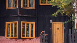 A two-story building with a dark facade, yellow-framed windows, and a wooden door. - Villa Sara in Sinaia near Peles & Gondola (Sinaia)