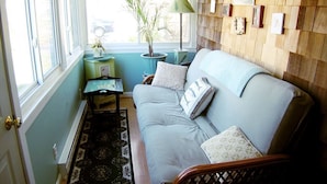 Una habitación acogedora con un sofá azul claro, una mesita auxiliar con una lámpara, una planta en maceta y un panel de pared de madera.