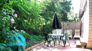 Un patio con una mesa y sillas, una mesa cubierta y una planta en maceta.