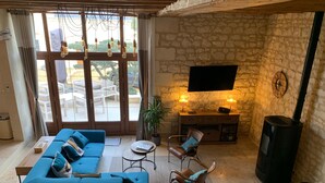 A living room with a sofa, chairs, a TV, a fireplace, and a view through large windows.