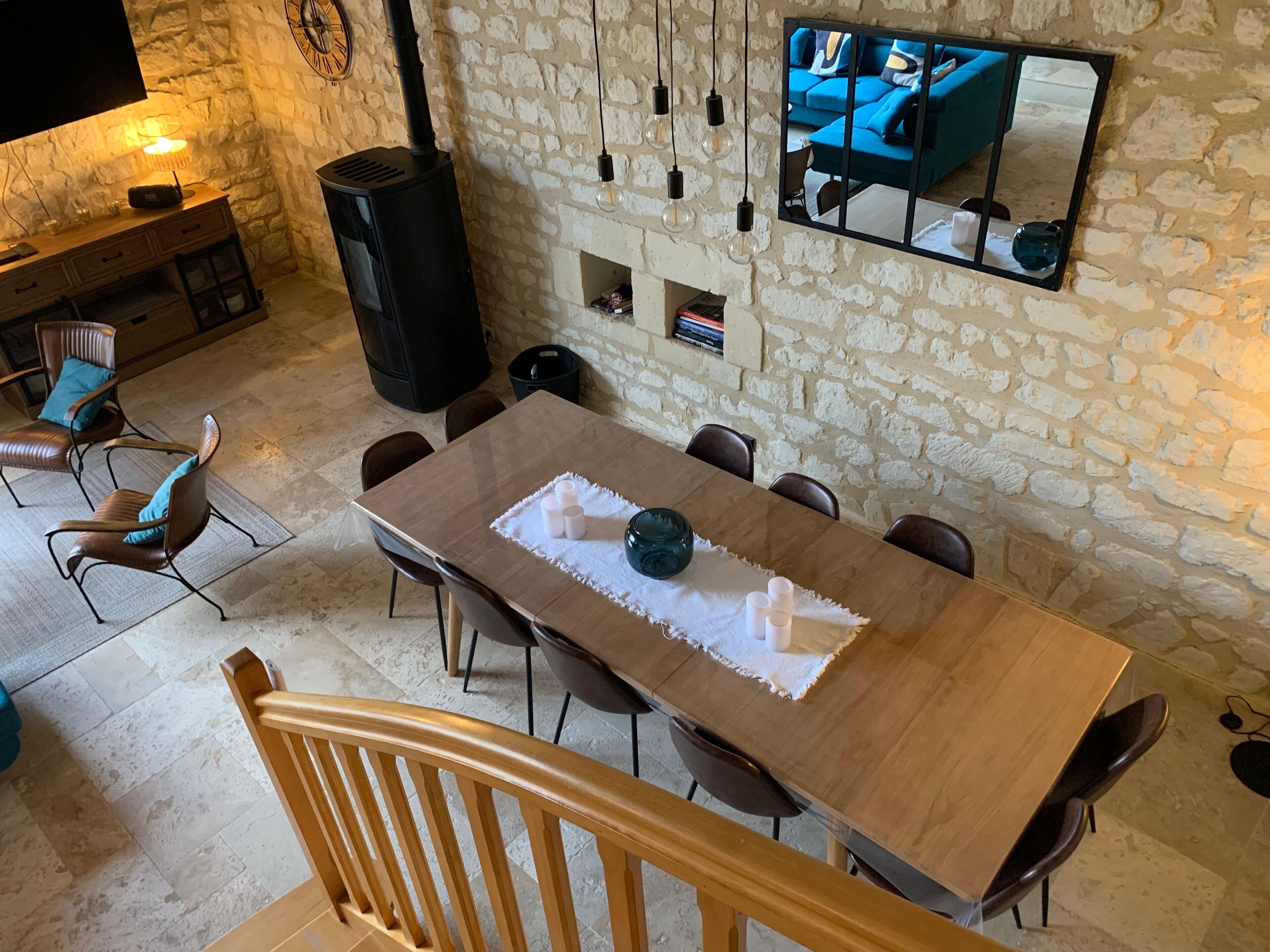 Ein Essbereich mit Holztisch, Stühlen, einer Steinwand, einem Fernseher und einem Kamin.