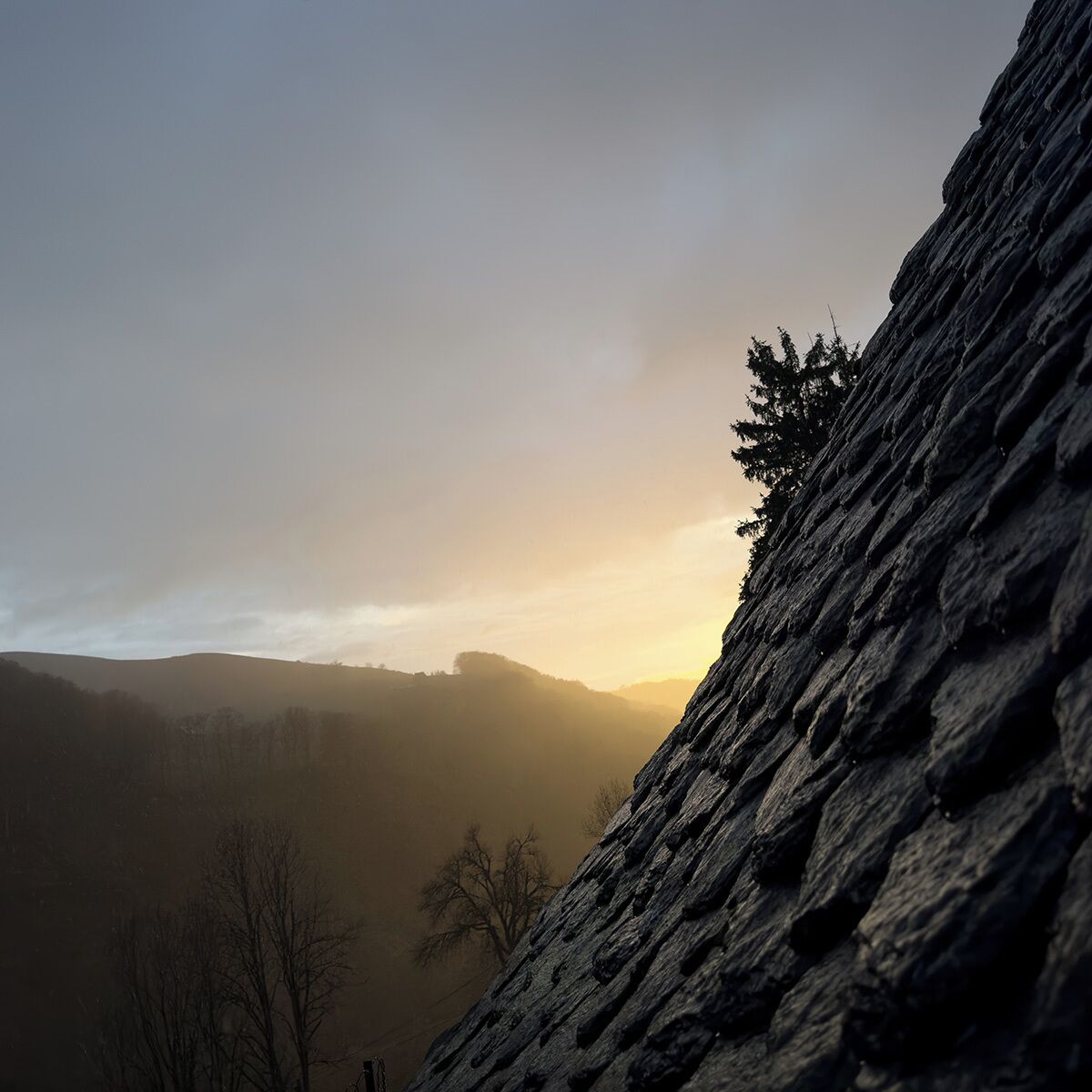 A rugged cliff with a forested valley in the background.