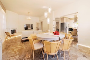 Uma sala de jantar moderna com uma mesa redonda, cadeiras de vime e um candelabro.