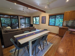 Un espace de vie moderne comprenant une table à manger, des chaises, un canapé et un coin cuisine.