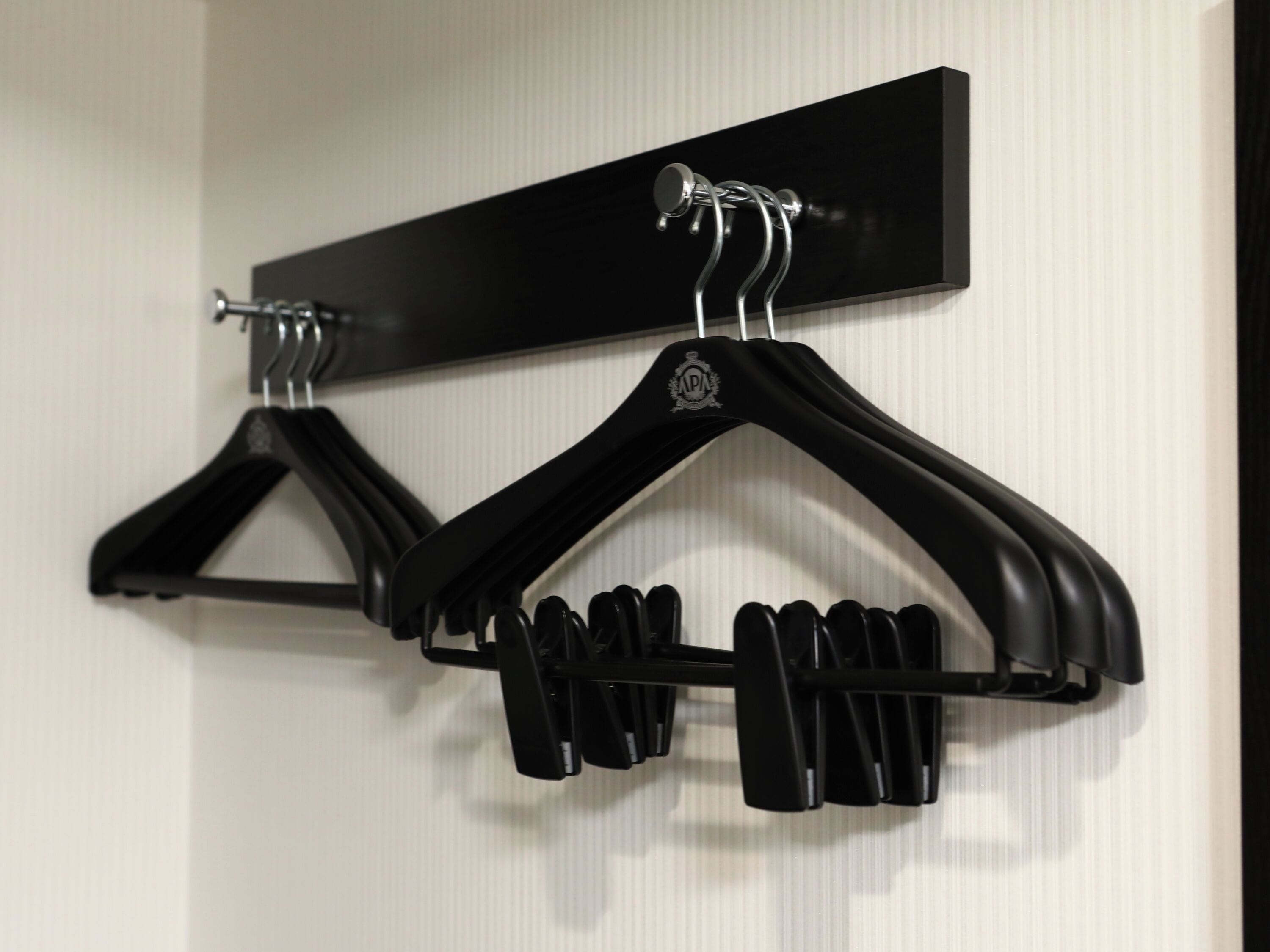 A wall-mounted coat rack with two black hangers.