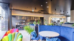 A modern interior with a curved blue seating area, a round table, and a bar in the background. - APA Hotel Hiroshima Ekimae Stadium Guchi (Hiroshima)