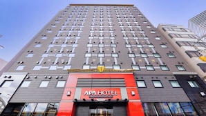 Een hoog hotelgebouw met een opvallende rode en zwarte gevel, veel ramen en een duidelijke entree.