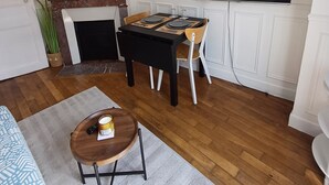 Una sala de estar con chimenea, una mesa de comedor con sillas, un televisor montado en la pared y un sofá.