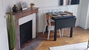 Un área de comedor con chimenea, una mesa, sillas y un televisor montado en la pared.