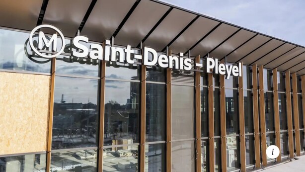 Un edificio moderno con grandes ventanales y un cartel que dice 'Saint Denis - Pleyel'.