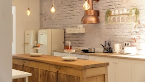 Een keuken met een houten aanrecht, hangende lampen, een bakstenen muur en witte apparaten.