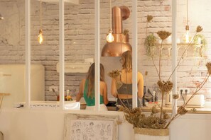 A modern kitchen with a brick wall, a large mirror, and hanging lights. - CORSICA HOSTEL PORTO VECCHIO (Porto-Vecchio)