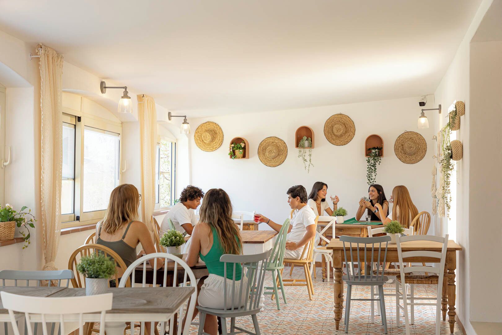 Een eetgedeelte met een groep mensen aan een tafel, omringd door rieten wanddecoraties en potplanten.