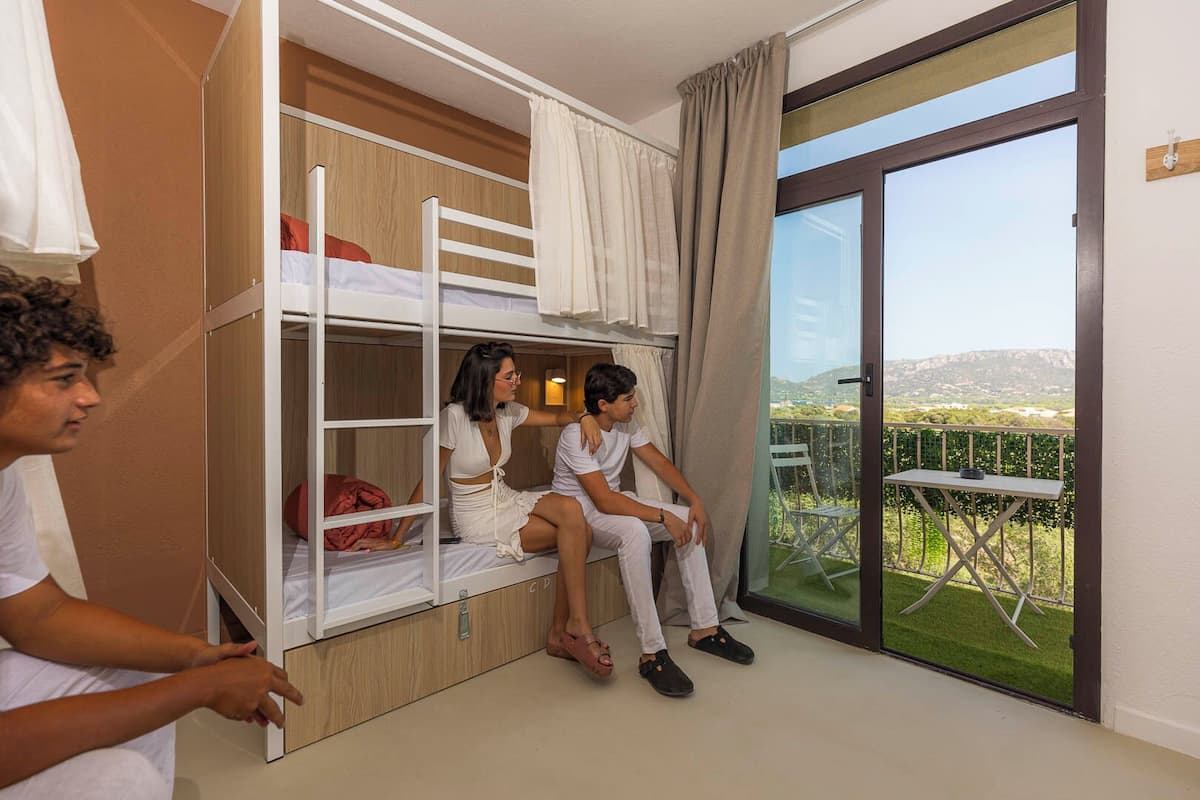 Ein Zimmer mit Etagenbetten, einem Balkon mit Tisch und Blick auf die Landschaft.