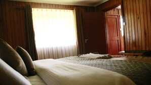A room with a bed, a window with curtains, and a wooden door. - Anabas Mount Kenya Lodge (Igoji)