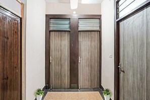 Un pasillo con dos puertas de madera, una lámpara y un tapete pequeño.