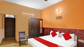 A hotel room with a bed, a wardrobe, a chair, and a door. - Vishen Residency (Greater Noida)