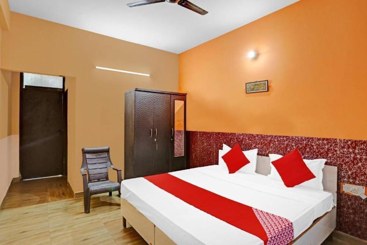 A hotel room with a bed, a wardrobe, a chair, and a door.
