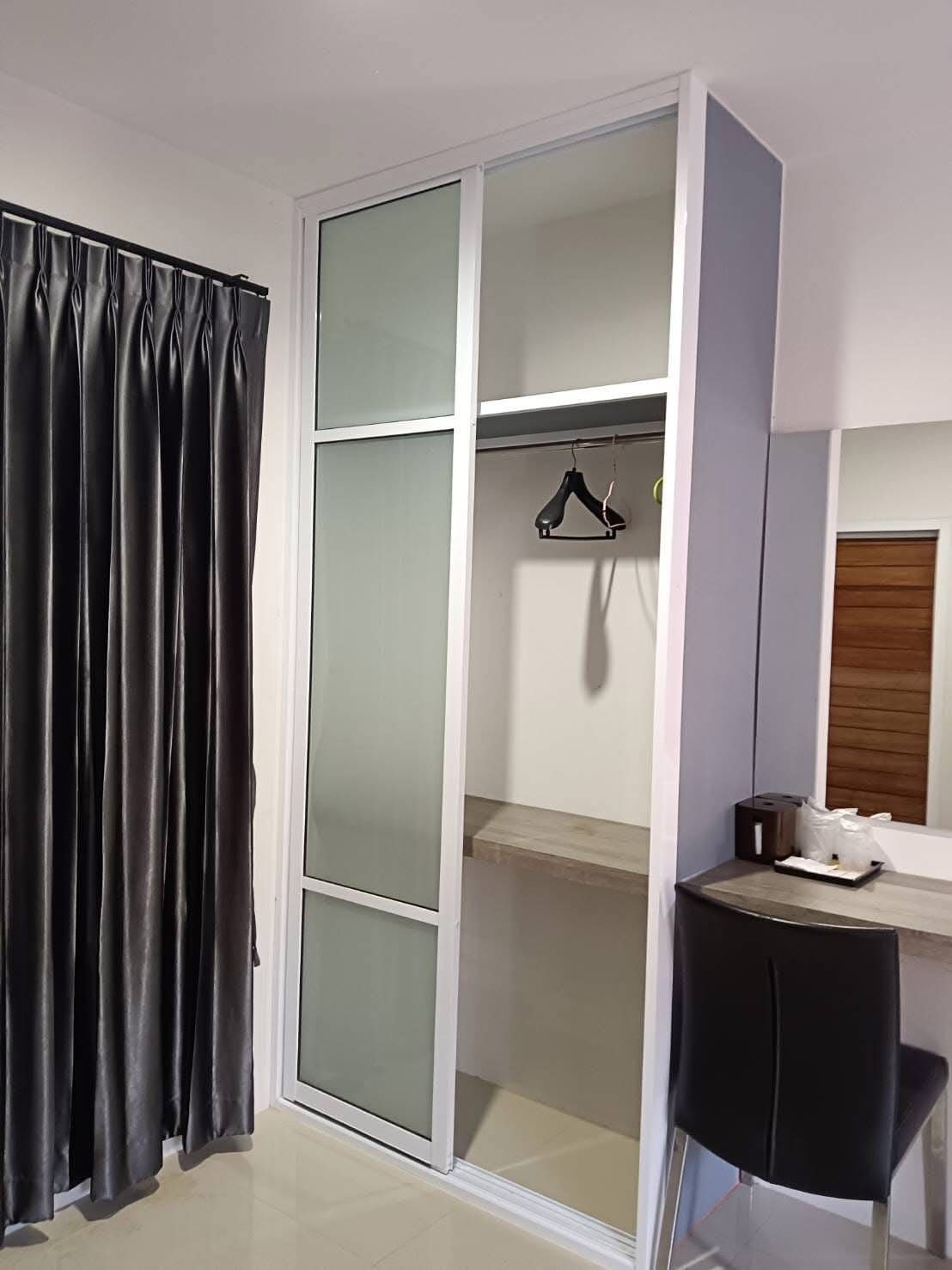 Ein Zimmer mit Schiebetüren zum Kleiderschrank, einem schwarzen Stuhl, einem kleinen Tisch und einer Kleiderstange.