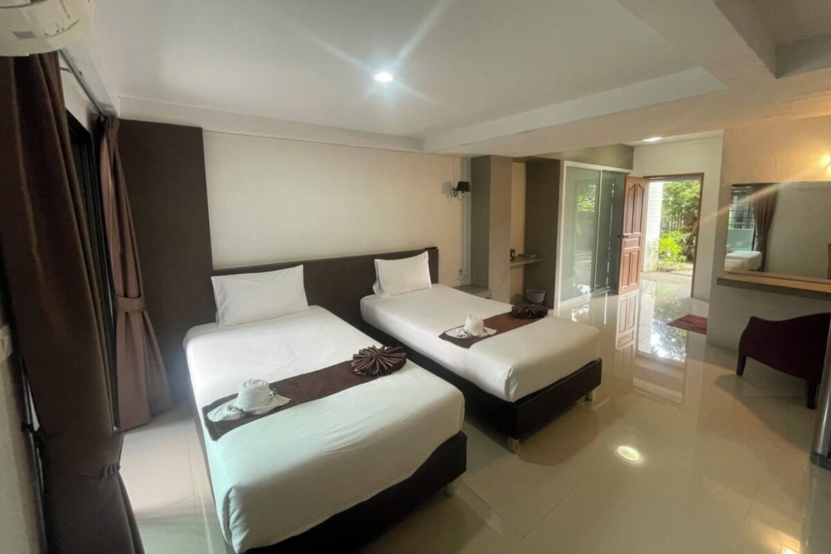 A hotel room with two beds, a bathroom, and a view of the outdoors.
