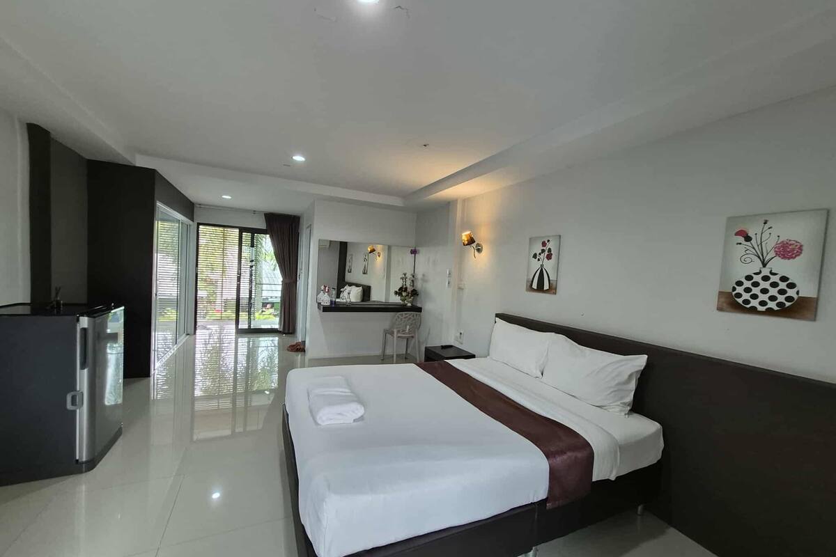 A modern hotel room with a large bed, a desk, and a view of the outdoors.