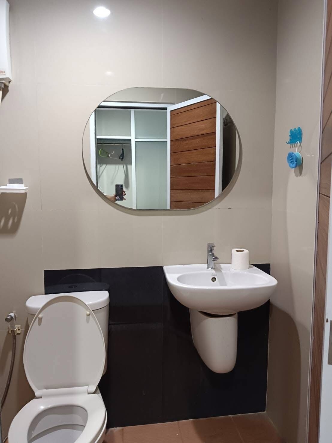 A bathroom with a toilet, sink, and mirror.